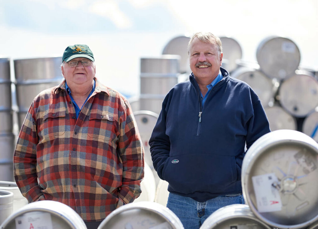 two men standing by barrels